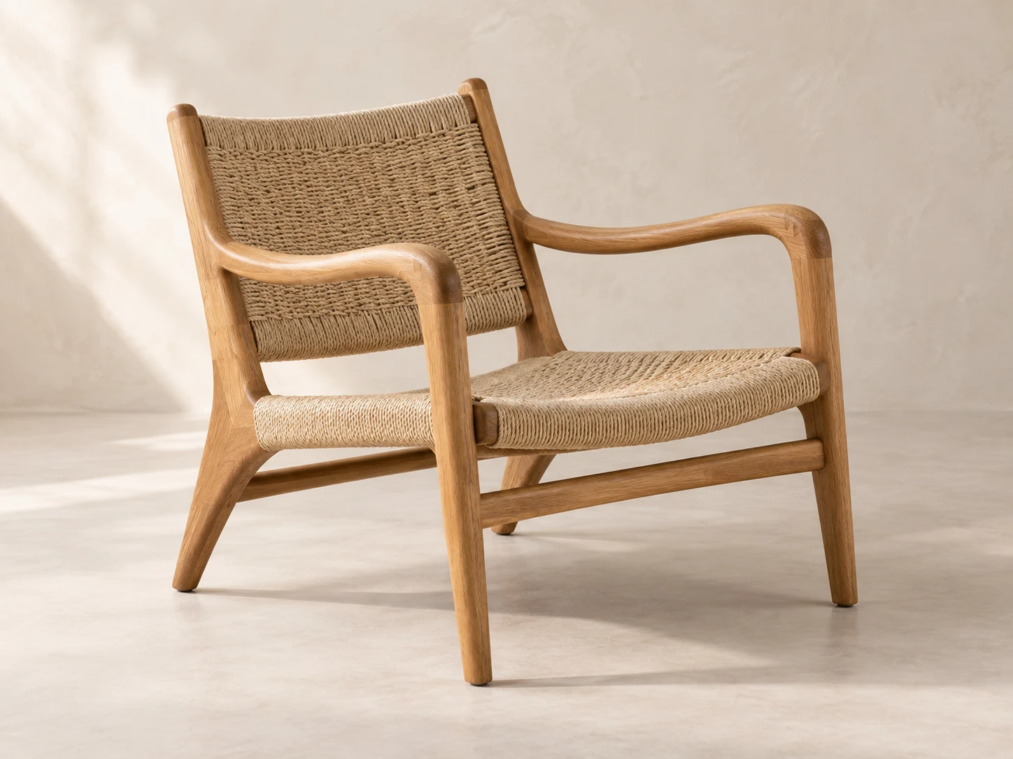 An oak lounge chair with a woven rope seat and back, photographed at a three-quarter angle.