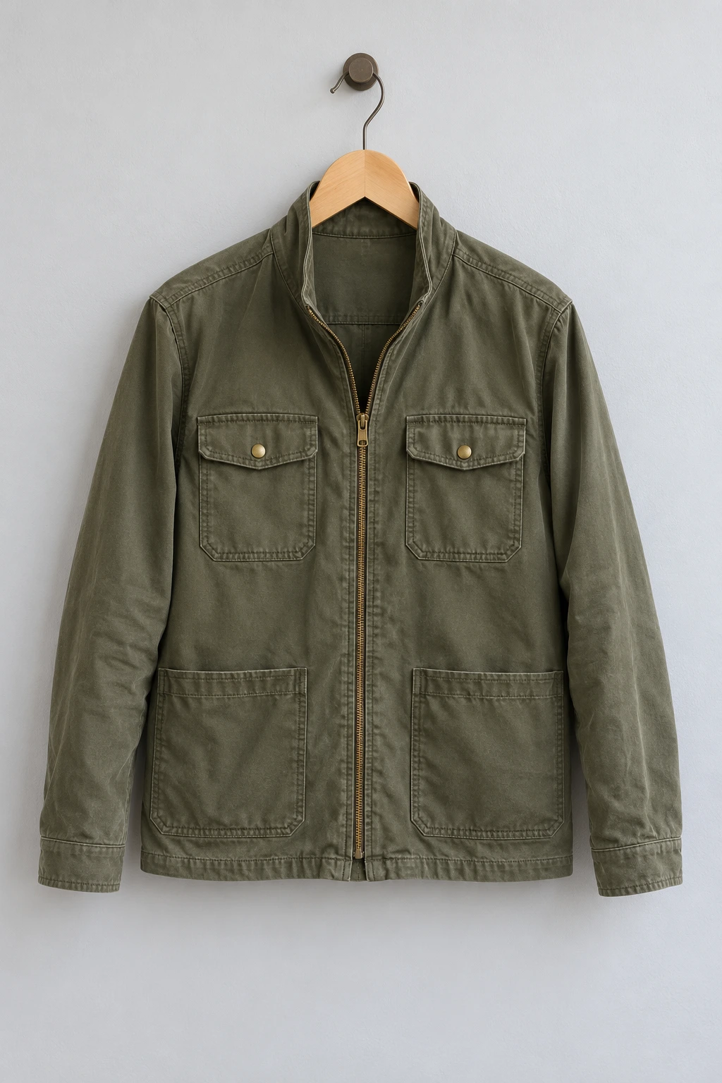 Olive utility jacket suspended from a wooden hanger.