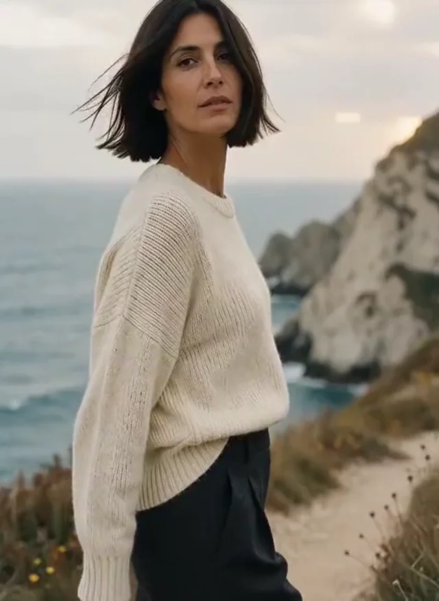 Woman in ivory knitwear on a windswept coastal path