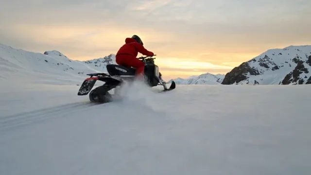 Snowmobile rider carving through alpine powder at sunrise
